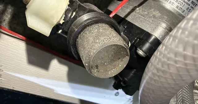 Broken RV water pump inlet strainer caused by freeze damage discovered during RV spring de-winterization plumbing inspection.